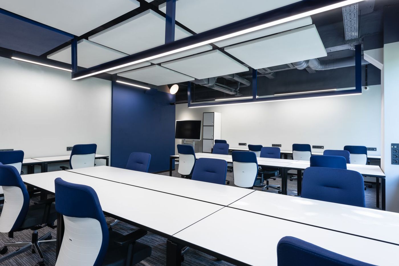 Sala de trabajo con islas acústicas blancas suspendidas del techo